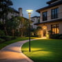 V-TAC Lotus LED-solcellehavelampe lyser op langs en havesti mellem græsplæne, buske og hus.