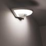 Den tændte V-TAC LED-væglampe ses skråt nedefra med PIR-sensoren synlig under lampen.
